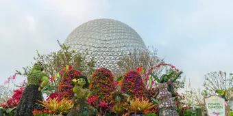 Topiaries of the Encanto characters in front colourful flowers and Spaceship Earth