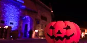 A jack-o'-lantern on the ground in front of a stone building at night