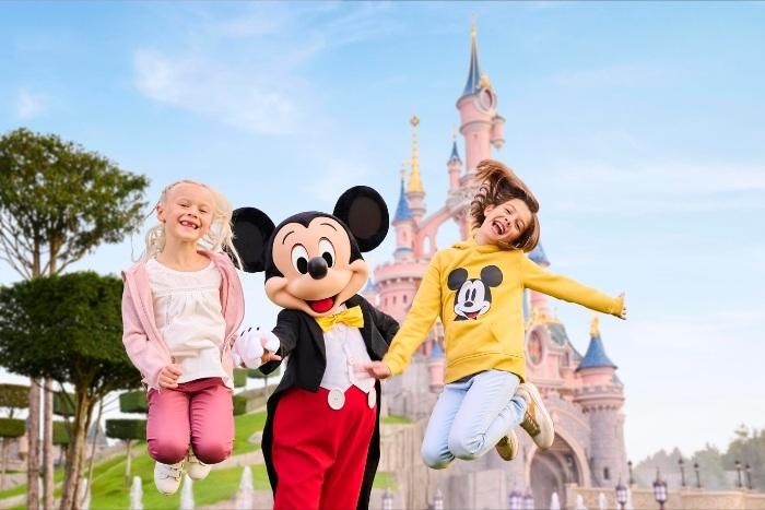 Mickey Mouse jumps in the air with 2 girls