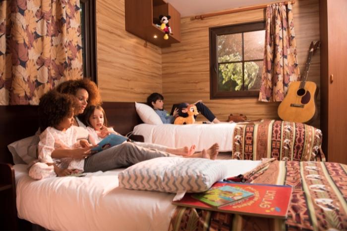 Family in a cosy hotel room reading books together on the bed