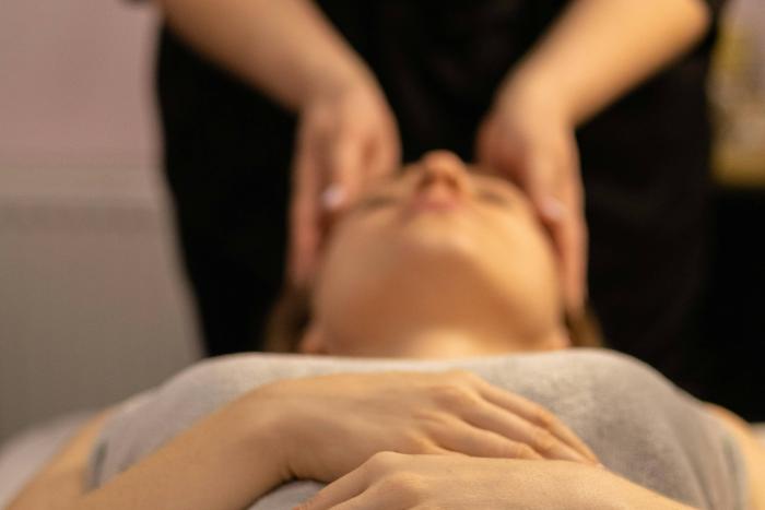 Woman lying in a spa in a relaxed state, receiving a head massage