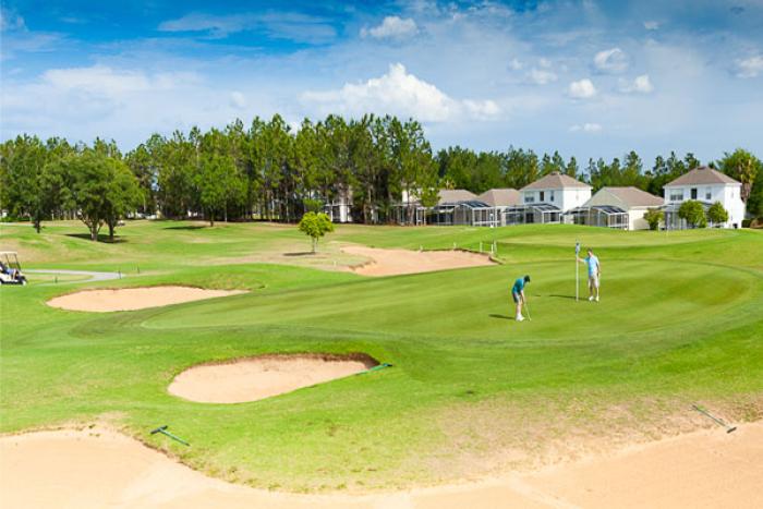 Golfers putting on the green at Highlands Reserve golf course, with homes in the background
