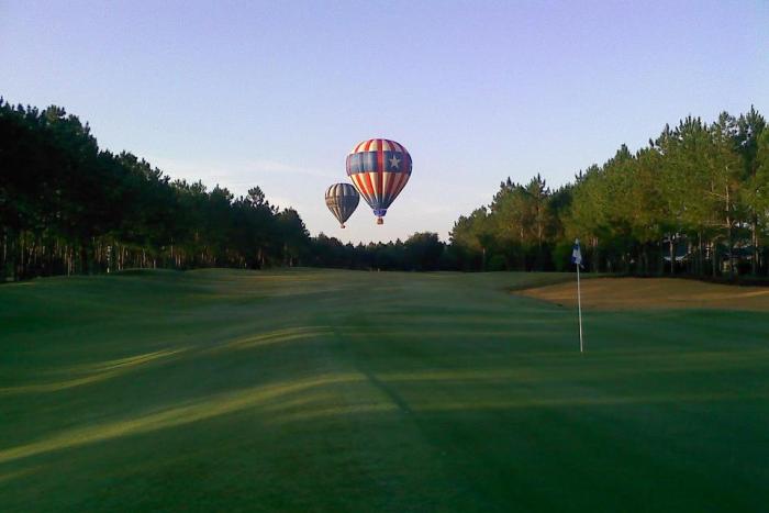 Hot air balloons floating over the golf course green at Highlands Reserve