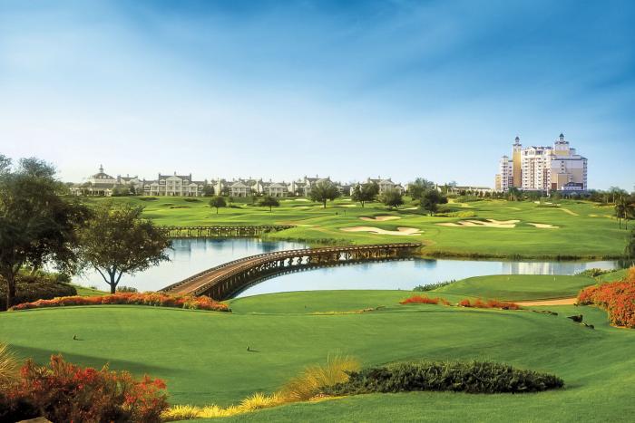 Golf course fairway with wooden bridge over water and Reunion Resort tower in the background