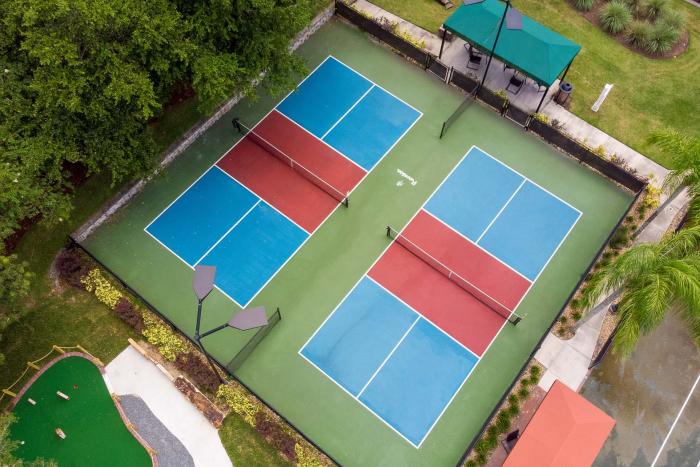 Aerial view of blue and red pickleball courts surrounded by greenery at Reunion Resort