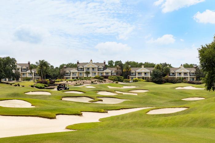 Golf course with sand bunkers and golf cart in front of resort villas at Reunion Resort