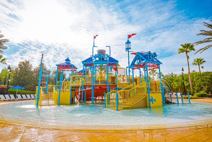 Colorful interactive water play structure with slides at Reunion Resort's family pool area