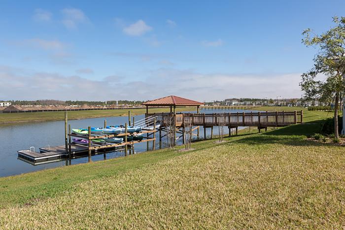 Wooden dock with a covered gazebo and a rack of colorful kayaks next to a lake