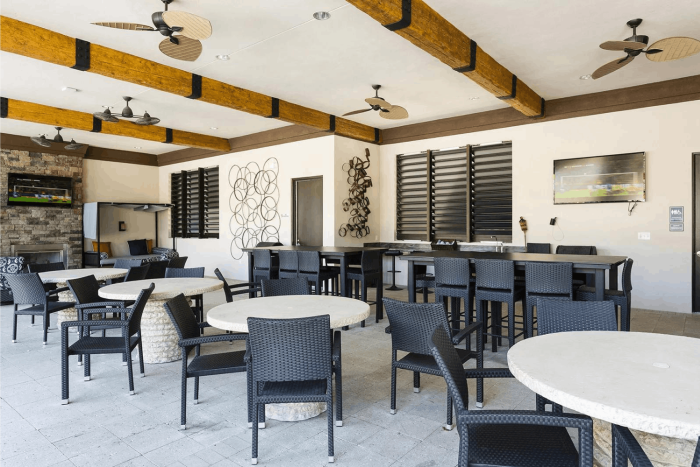 Covered outdoor patio at Solterra Resort featuring dark wicker chairs, round tables, high-top bars, and ceiling fans.