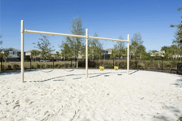 Outdoor swing set with belt swings and toddler bucket seats in a white sand playground at Solterra Resort.