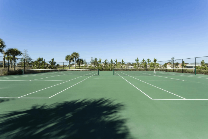 Two green outdoor tennis courts side-by-side with white lines and nets under a clear blue sky at Solterra Resort.
