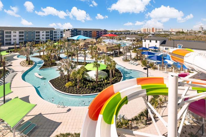 Elevated view of a winding lazy river pool surrounded by palm trees and resort buildings