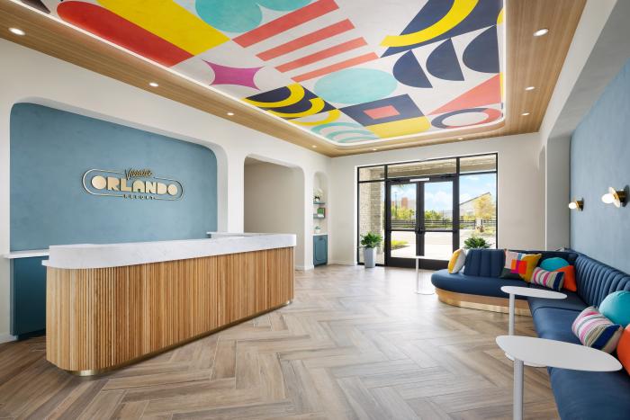 Villatel Orlando Resort reception desk with a wood-paneled counter and a colorful geometric ceiling mural