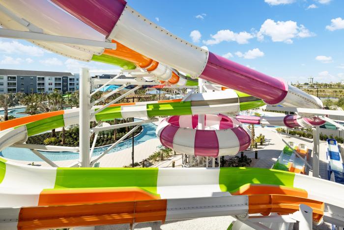 Close-up of colorful twisting green, pink, and orange water slides at a resort water park