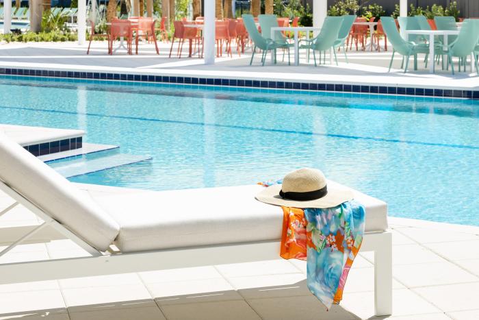 Sun lounger beside a swimming pool with a straw sun hat and colorful sarong