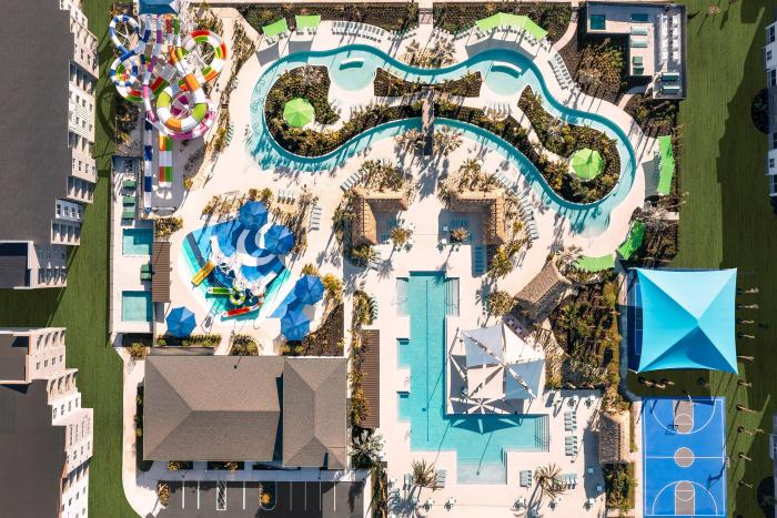 Overhead aerial view of a luxury resort pool complex featuring a lazy river, splash pad, and sports courts