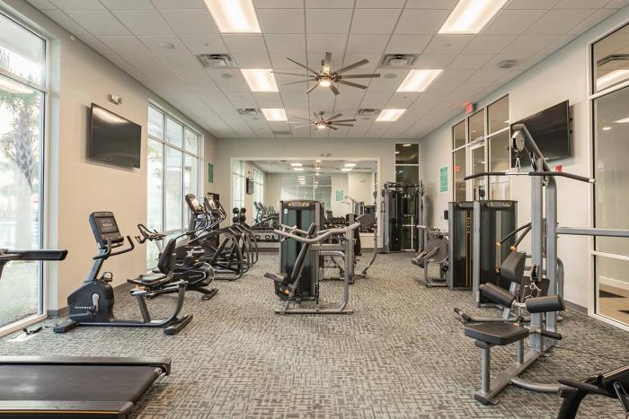 A brightly lit resort gym featuring rows of Matrix treadmills, stationary bikes, elliptical machines, and weight training equipment.