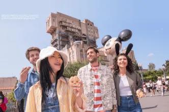A group of four friends in their twenties walking in front of Tower of Terror in Walt Disney Studios