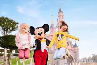 Two young girls jumping with Mickey Mouse in front of the Disneyland Paris castle