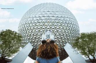 A young girl wearing Minnie ears facing towards Spaceship Earth at EPCOT
