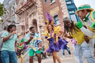 People dancing with Mardi Gras performers dressed in bright coloured, feathered costumes