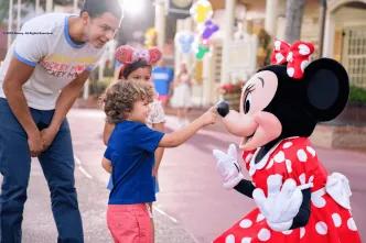 A young boy touching Minnie Mouse on the tip of her nose