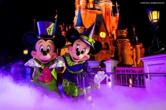 Mickey and Minnie Mouse in Halloween costumes standing in front of Cinderella Castle