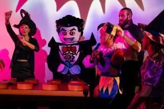 LEGOLAND Dubai Halloween Dracula lego character danging by lego dj deck with kids gethered around wearing halloween costumes.