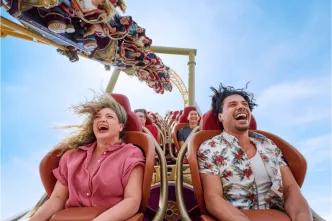 Two adults laughing and screaming with their hair flying while riding a high-speed roller coaster at Universal Orlando Resort, illustrating the kind of thrill ride experience you secure by booking tickets in advance.