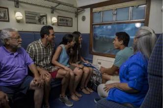 A multigenerational family riding the enclosed Hogwarts Express attraction at Universal Orlando Resort, enjoying the scenic views outside the compartment window, a perfect activity when it's raining.