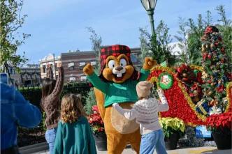 Children waving at a friendly squirrel character, surrounded by Christmas decorations and red poinsettias, capturing a joyful holiday season moment and a memorable experience in Orlando.
