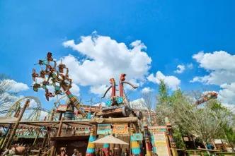 A wide view of the colorful How to Train Your Dragon – Isle of Berk land at Universal Epic Universe, featuring the towering Dragon Racer's Rally ride structure against a bright blue sky.