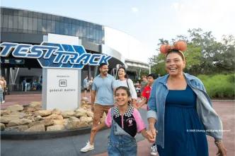 A happy family laughing together while walking past the Test Track attraction at EPCOT, Walt Disney World in Florida