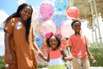 A joyful family surrounded by colorful Disney-themed balloons and bubbles at Walt Disney World