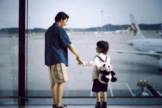 A father and son looking out the window at an airport