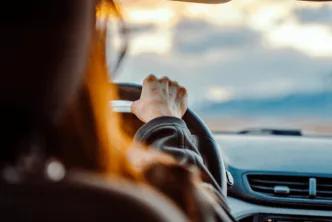 Over-the-shoulder view of a person holding a steering wheel while driving