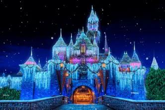 Sleeping Beauty Castle at Disneyland Resort glowing at night with shimmering icicle lights, holiday wreaths, snow-capped turrets, and falling snow effect