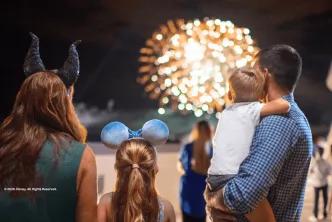 A family wearing Disney ears looking out at a nighttime fireworks display