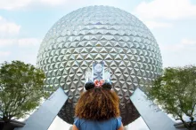 A girl looking up at Spaceship Earth, a large geodesic sphere