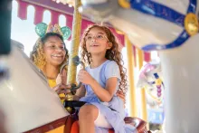 A girl and her mother riding a traditional carrousel