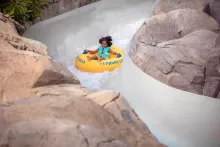 A young girl on a raft going down a water slide