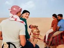 Bedouin Culture Safari Dubai Guests enjoying a camel ride through the Dubai desert