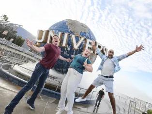 Universal Orlando Resort Three people jumping excitedly in front of the Universal Globe