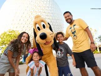 Walt Disney World Resort in Florida  A mother and father with a young boy and young girl posing with Pluto in front of Spaceship Earth