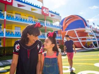 Disney's All-Star Sports Resort A woman and girl walking in front of a hotel designed to look like an American football pitch