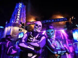 Two costumed Fortnite characters posing in front of an illuminated Halloween Horror Nights sign at Universal Studios