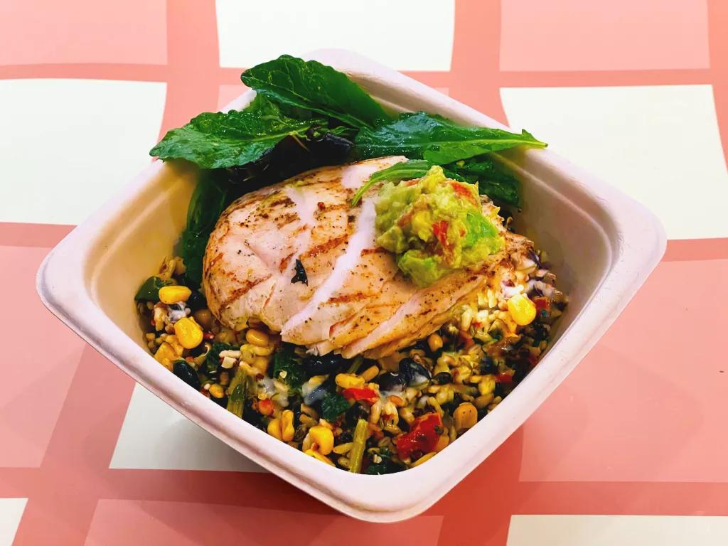 Exotic Grains Bowl A bowl of mixed grains and vegetables topped with chicken and avocado