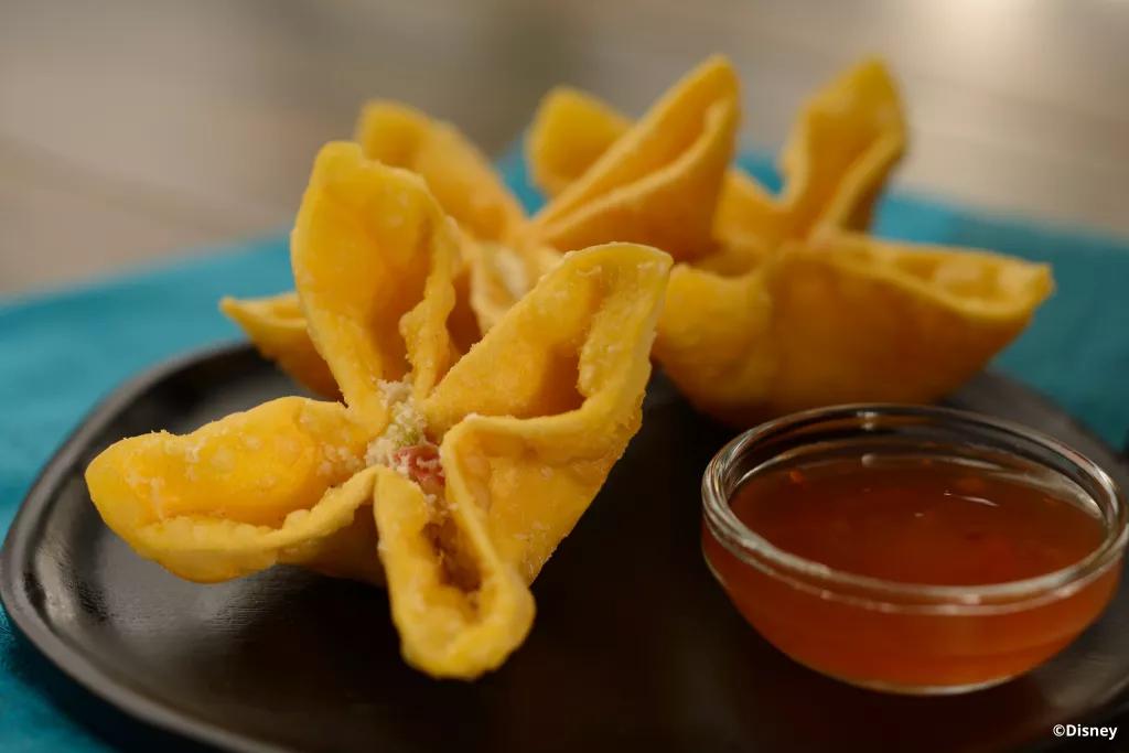 Cheesy Crab Wontons at Lotus House Three crispy wontons on a plate with chilli dipping sauce