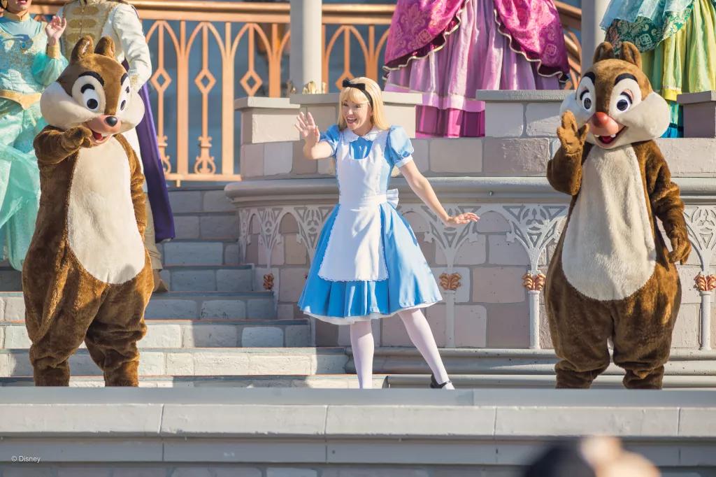 Magic Kingdom Welcome Show Alice, Chip and Dale waving to guests from Cinderella Castle Stage