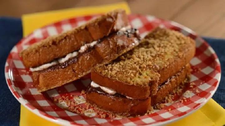 Smores French Toast Sandwich A toasted sandwich filled with marshmallow and chocolate on a gingham patterned plate